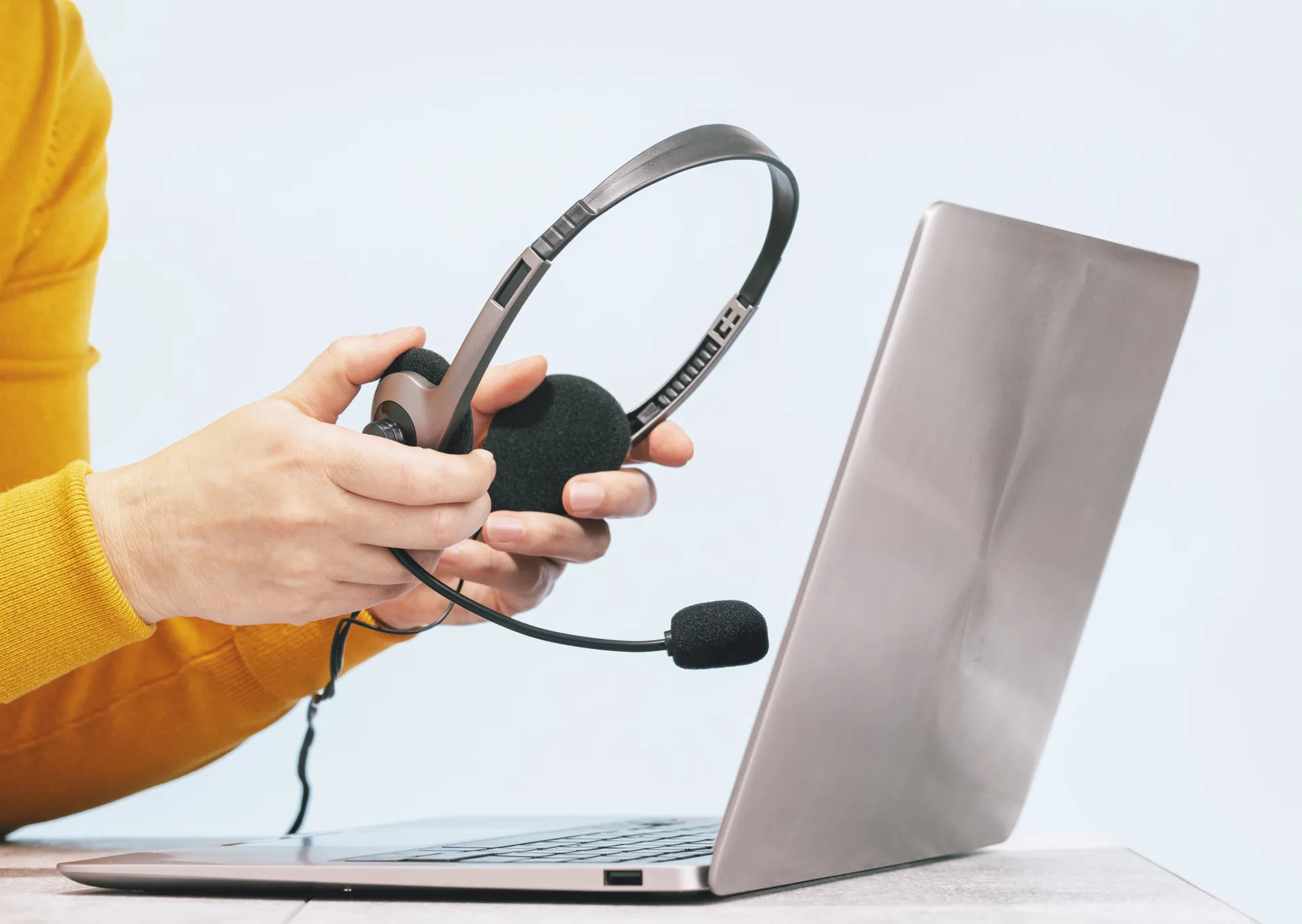 Hände mit Headset vor einem Laptop